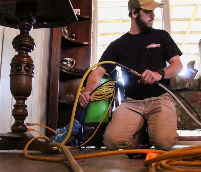 SERVPRO's Crew Chief cleaning floor ducts with a compressed air hose.